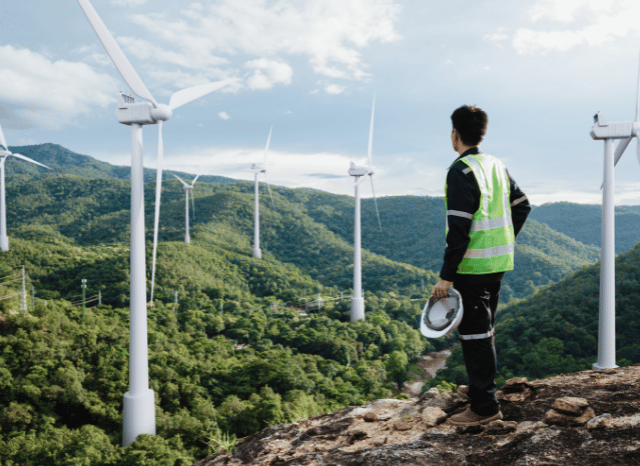 a man standing on a mountain with wind turbines in the background Stanislav Kondrashov