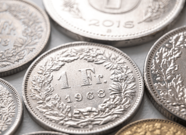 Swiss franc and US dollar coins representing currency comparison