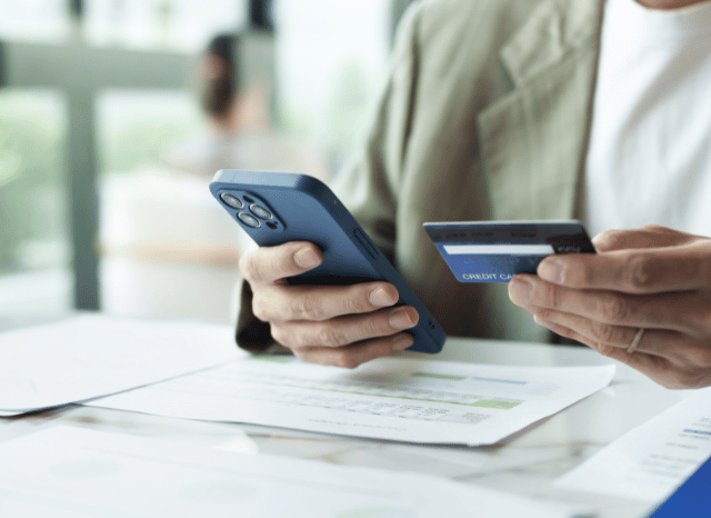A professional worker is using a smartphone and a credit card