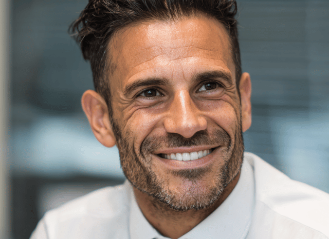 A smiling man looks at the camera